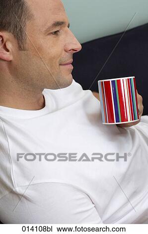 portrait of young man relaxing with coffee cup on sofa View Large Photo Image Stock Image - portrait of young man relaxing with coffee cup on sofa. Fotosearch