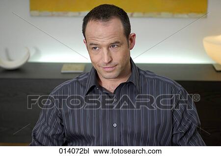 Stock Image - portrait of young man sitting in striped shirt. Fotosearch