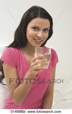 Stock Image - portrait of young woman holding glass of water. Fotosearch