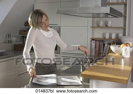 portrait of young woman in kitchen talking on cellphone, cooking and reading magazine View Large Photo Image Stock Image - portrait of young woman in kitchen talking on cellphone, cooking and reading magazine. Fotosearch