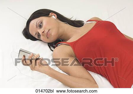 portrait of young woman lying on bed listening to music on ipod View Large Photo Image Stock Image - portrait of young woman lying on bed listening to music on ipod. Fotosearch