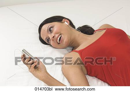 portrait of young woman lying on bed listening to music on ipod View Large Photo Image Stock Image - portrait of young woman lying on bed listening to music on ipod. Fotosearch