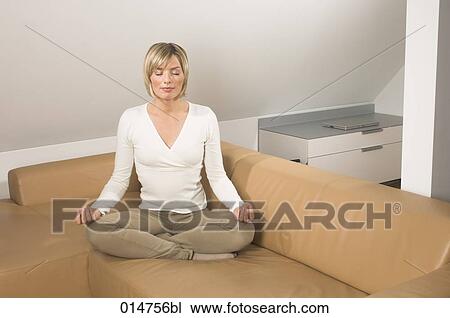 portrait of young woman meditating on sofa in living room View Large Photo Image Stock Image - portrait of young woman meditating on sofa in living room. Fotosearch