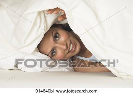 portrait of young woman peeking through bedcovers View Large Photo Image Stock Image - portrait of young woman peeking through bedcovers. Fotosearch