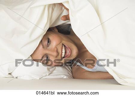 portrait of young woman peeking through bedcovers View Large Photo Image Stock Image - portrait of young woman peeking through bedcovers. Fotosearch