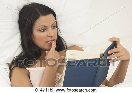 portrait of young woman reading exciting book in bed View Large Photo Image Stock Image - portrait of young woman reading exciting book in bed. Fotosearch