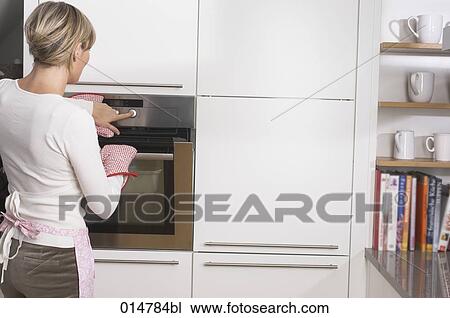 rear view of blonde housewife standing at oven View Large Photo Image Stock Image - rear view of blonde housewife standing at oven. Fotosearch