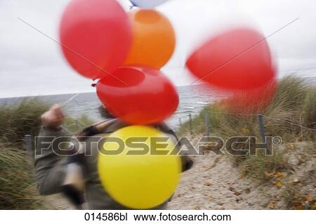rear view of woman on windy beach in autumn holding colourful balloons View Large Photo Image Stock Image - rear view of woman on windy beach in autumn holding colourful balloons. Fotosearch
