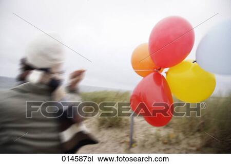rear view of woman with scarf on windy beach in autumn holding colourful balloons View Large Photo Image Stock Image - rear view of woman with scarf on windy beach in autumn holding colourful balloons. Fotosearch