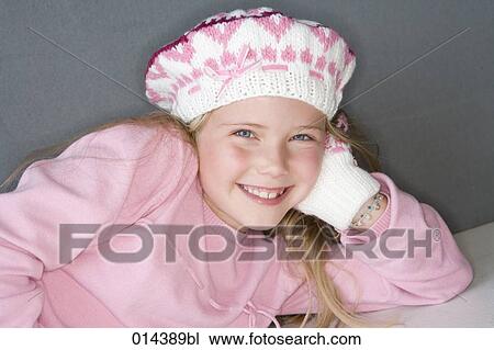Stock Image - smiling young girl in pink winter clothes looking at camera. Fotosearch