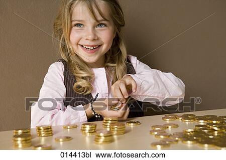 Stock Image - smiling young girl playing with gold coins. Fotosearch