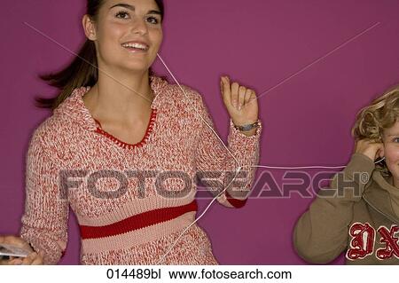 Stock Image - teenage girl dancing to music with her brother. Fotosearch