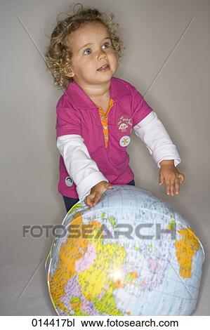Stock Image - toddler playing with inflatable globe. Fotosearch