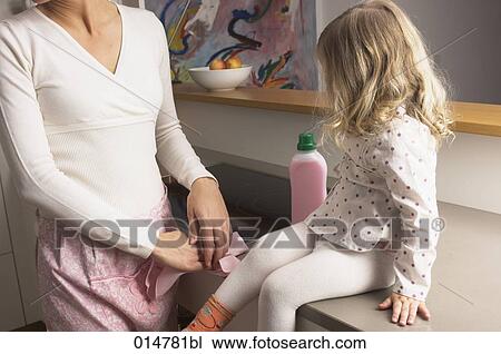 Stock Image - toddler watching her mother cleaning the kitchen. Fotosearch