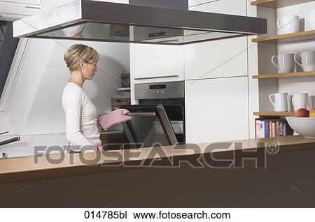 view into kitchen with housewife opening oven door View Large Photo Image Stock Image - view into kitchen with housewife opening oven door. Fotosearch