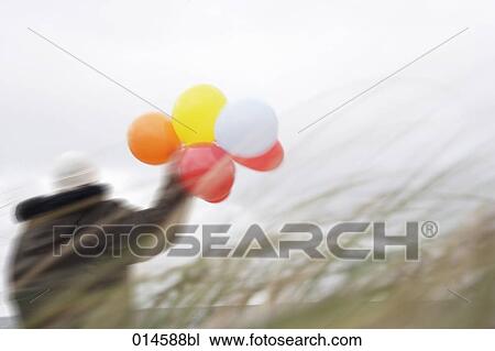 woman holding colourful balloons on windy beach View Large Photo Image Stock Image - woman holding colourful balloons on windy beach. Fotosearch