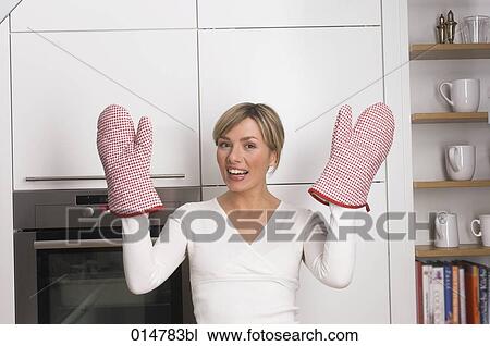 young blonde housewife standing in kitchen showing oven mitts View Large Photo Image Stock Image - young blonde housewife standing in kitchen showing oven mitts. Fotosearch
