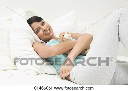young woman lying in bed holding little teddy bear View Large Photo Image Stock Image - young woman lying in bed holding little teddy bear. Fotosearch