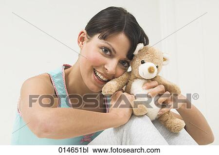 young woman lying in bed holding little teddy bear View Large Photo Image Stock Image - young woman lying in bed holding little teddy bear. Fotosearch