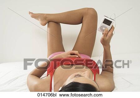 young woman lying on bed listening to music on ipod View Large Photo Image Stock Image - young woman lying on bed listening to music on ipod. Fotosearch