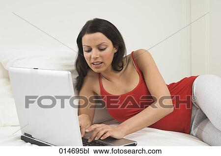 young woman lying on bed with laptop computer View Large Photo Image Stock Image - young woman lying on bed with laptop computer. Fotosearch