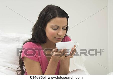 young woman sitting in bed smelling hot drink View Large Photo Image Stock Image - young woman sitting in bed smelling hot drink. Fotosearch