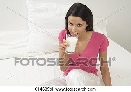 young woman sitting on bed drinking glass of milk View Large Photo Image Stock Image - young woman sitting on bed drinking glass of milk. Fotosearch
