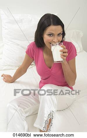 young woman sitting on bed drinking glass of milk View Large Photo Image Stock Image - young woman sitting on bed drinking glass of milk. Fotosearch