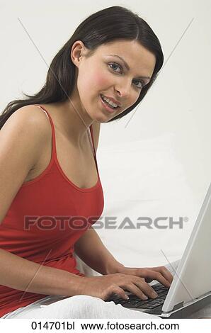 Stock Image - young woman with laptop computer looking at camera. Fotosearch