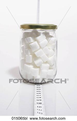 Stock Image - jar filled with sugar cubes standing on tape measure. Fotosearch