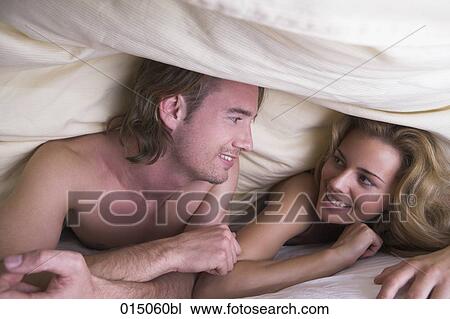 portrait of couple under bedcover smiling at each other View Large Photo Image Stock Image - portrait of couple under bedcover smiling at each other. Fotosearch