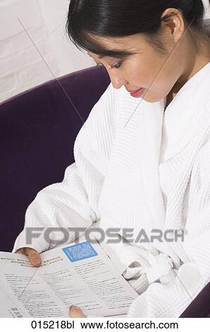 Stock Image - portrait of japanese woman in white bathrobe reading magazine. Fotosearch