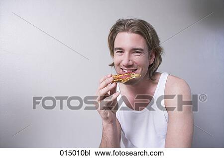 portrait of smiling young man in undershirt eating piece of pizza View Large Photo Image Stock Image - portrait of smiling young man in undershirt eating piece of pizza. Fotosearch