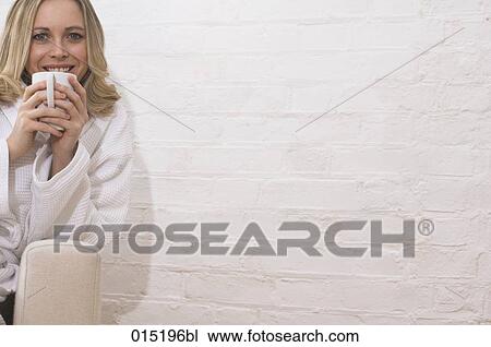 portrait of smiling young woman in bathrobe sitting on arm chair holding mug View Large Photo Image Stock Image - portrait of smiling young woman in bathrobe sitting on arm chair holding mug. Fotosearch
