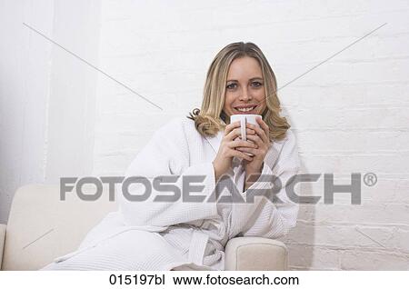 portrait of smiling young woman in bathrobe sitting on arm chair holding mug View Large Photo Image Stock Image - portrait of smiling young woman in bathrobe sitting on arm chair holding mug. Fotosearch