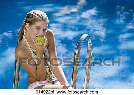 portrait of teenage girl sitting by swimming pool and biting into apple View Large Photo Image Stock Image - portrait of teenage girl sitting by swimming pool and biting into apple. Fotosearch