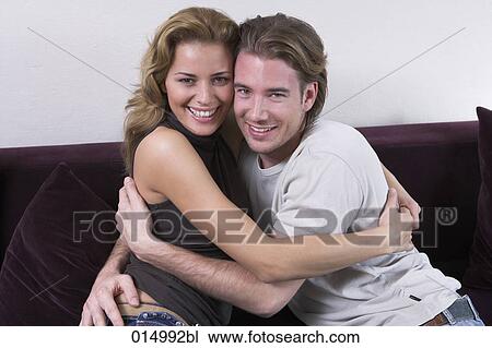 portrait of young couple embracing on couch View Large Photo Image Stock Image - portrait of young couple embracing on couch. Fotosearch