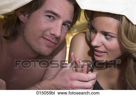 portrait of young couple holding hands under bedcover View Large Photo Image Stock Image - portrait of young couple holding hands under bedcover. Fotosearch