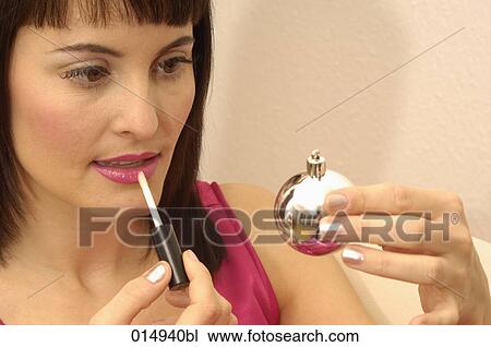 portrait of young woman applying lip-gloss using bauble as mirror View Large Photo Image Stock Image - portrait of young woman applying lip-gloss using bauble as mirror. Fotosearch