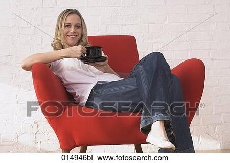 portrait of young woman relaxing on armchair drinking cup of coffee View Large Photo Image Stock Image - portrait of young woman relaxing on armchair drinking cup of coffee. Fotosearch
