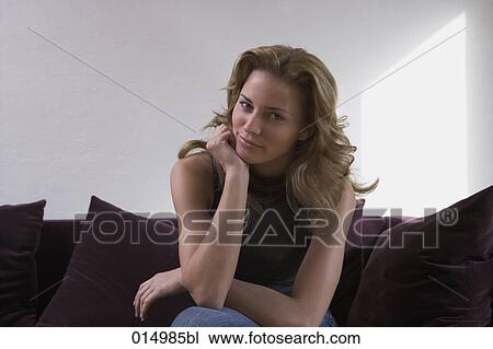 portrait of young woman sitting on sofa looking at camera View Large Photo Image Stock Image - portrait of young woman sitting on sofa looking at camera. Fotosearch