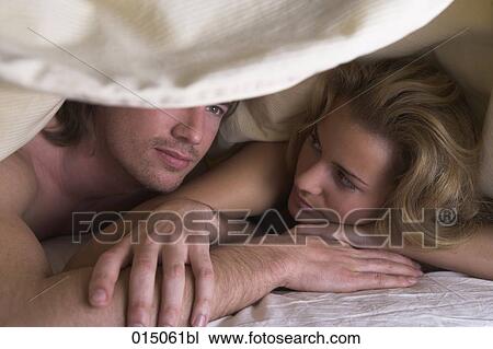 portrait young couple lying under bedcover man looking serious View Large Photo Image Stock Image - portrait young couple lying under bedcover man looking serious. Fotosearch