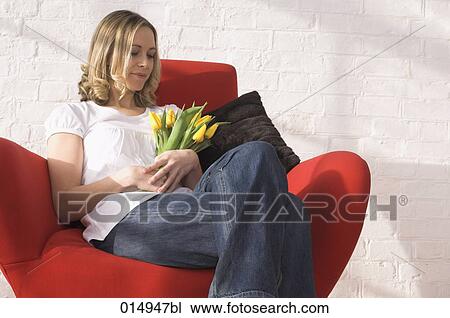 potrait of young woman sitting in armchair holding bunch of red tulips View Large Photo Image Stock Image - potrait of young woman sitting in armchair holding bunch of red tulips. Fotosearch