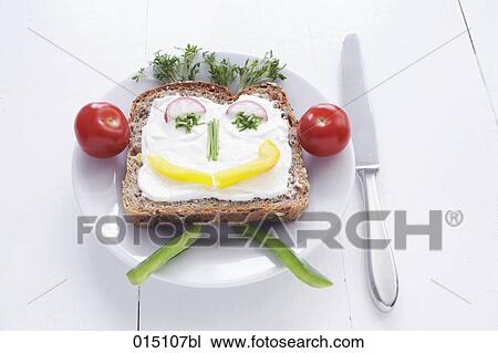 Stock Image - sandwich with cream cheese and face formed from different vegetables. Fotosearch