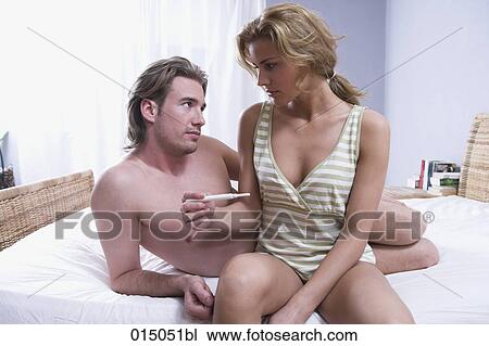 Stock Image - serious young couple sitting together woman holding pregnancy test. Fotosearch
