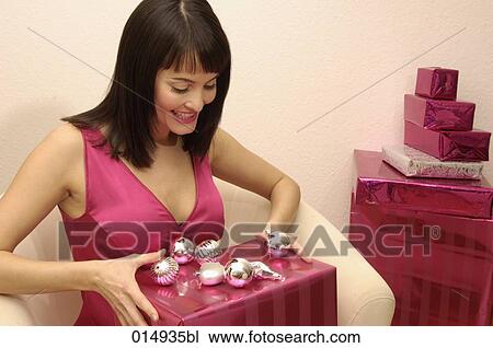 smiling young woman sitting on arm chair holding christmas present View Large Photo Image Stock Image - smiling young woman sitting on arm chair holding christmas present. Fotosearch