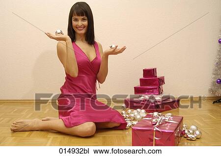 smiling young woman sitting on floor holding baubles surrounded by christmas presents View Large Photo Image Stock Image - smiling young woman sitting on floor holding baubles surrounded by christmas presents . Fotosearch