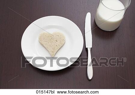 Stock Image - still life of bread cut out in shape of heart on plate and glass of milk. Fotosearch