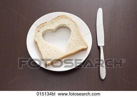 Stock Image - still life of bread with cut out shape of heart on plate. Fotosearch