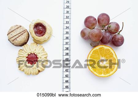 Stock Image - still life of cookies and fruits separated by tape measure. Fotosearch
